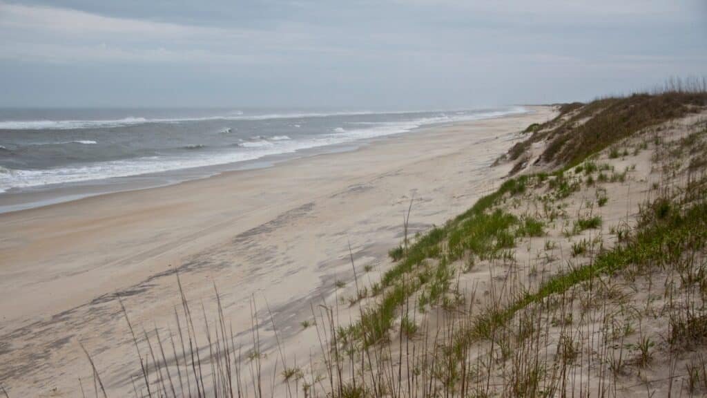 A wide empty beach running alongside a vegetated dune line on Hatteras Island.