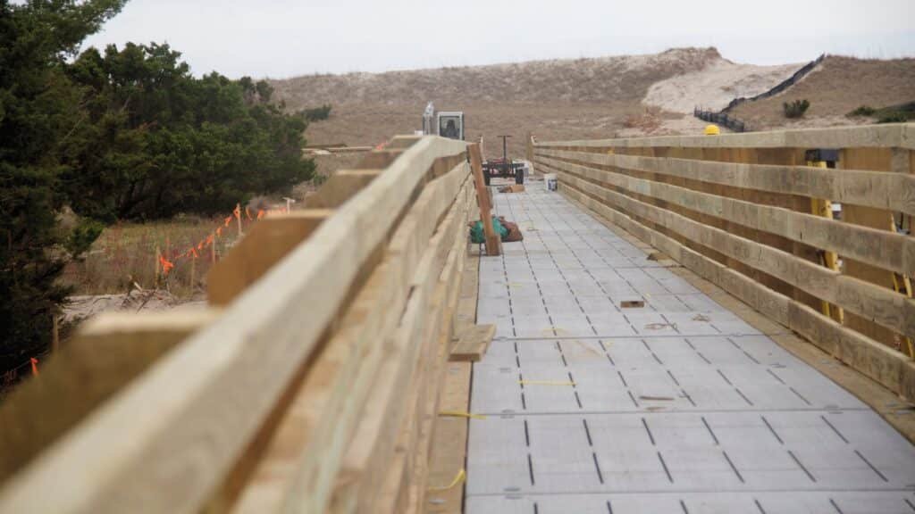 A wooden boardwalk and vehicle ramp leading over the dune line to the open beach.