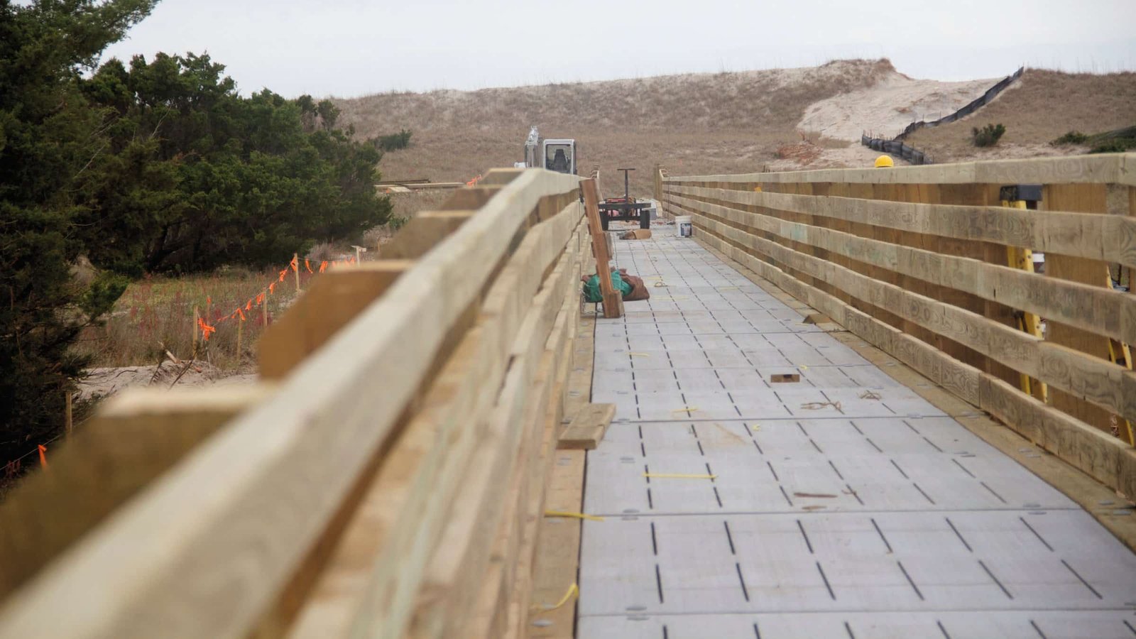 A wooden boardwalk and vehicle ramp leading over the dune line to the open beach.