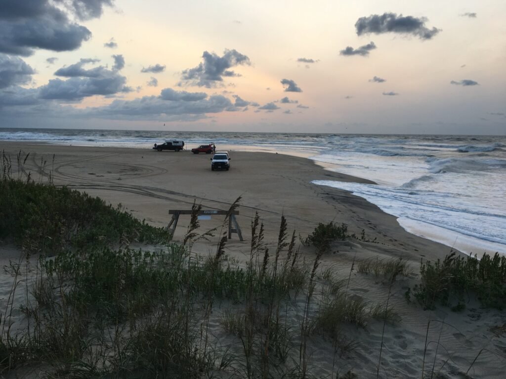 View toward Cape Point from the dune at the south end of the Bypass Road, with vehicles parked along the shoreline.