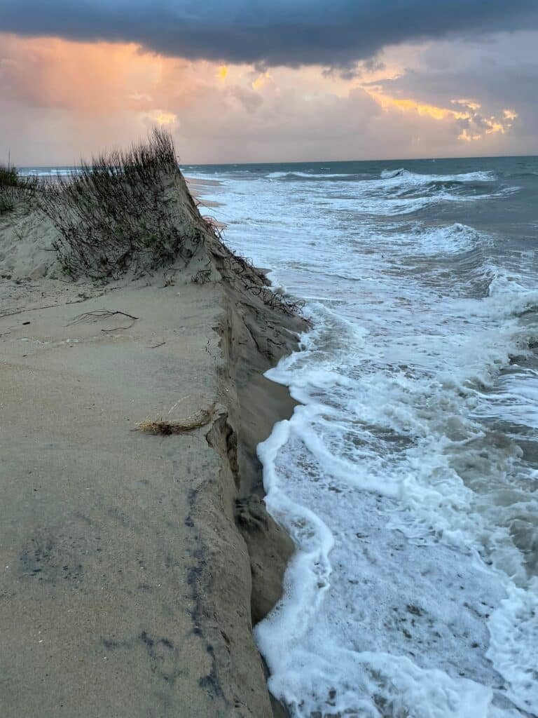 Waves breaking directly against a steep cut sand bank at the end of the Bypass Road south of Ramp 44.
