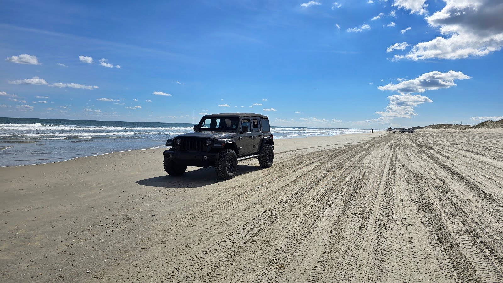 A Jeep driving the tracked sand of the Outer Banks 4x4 beach.