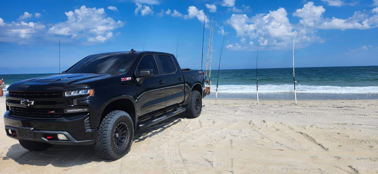 Chevy Silverado Z71 4x4 rental on the sand with rod holders and the surf behind